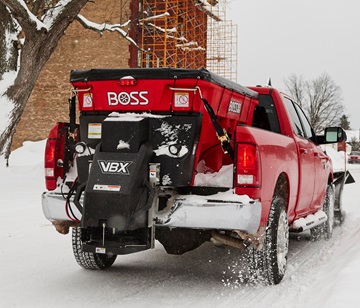Red pickup truck with BOSS snow plow clearing a residential street