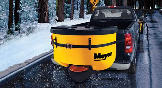 Black pickup truck with yellow Meyer tailgate spreader on a snowy road